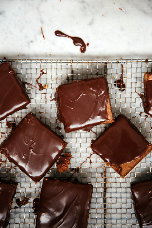 Load image into Gallery viewer, homemade brownies on a cooling rack topped with fudge sauce