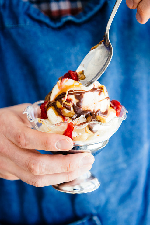 Load image into Gallery viewer, Person holding an ice cream sundae cup with a spoon, wearing a blue shirt