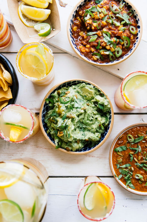Load image into Gallery viewer, bowls of guacamole, chips, salsa, bean dip, street corn dip and glasses of margaritas