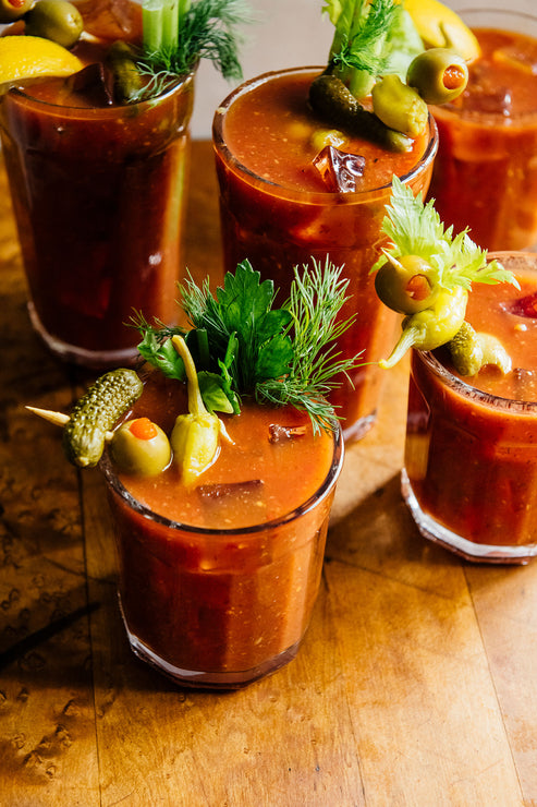 Load image into Gallery viewer, Bloody Mary cocktails with garnishes on a wooden surface