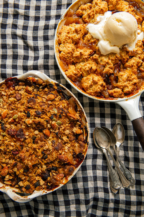 Load image into Gallery viewer, Two pans of peach cobbler with ice cream on a checkered tablecloth