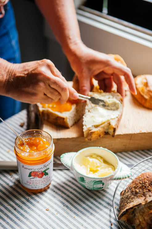 Load image into Gallery viewer, Loaves of bread with jars of Peach, Strawberry & Sour Cherry Preserves on a wooden surface