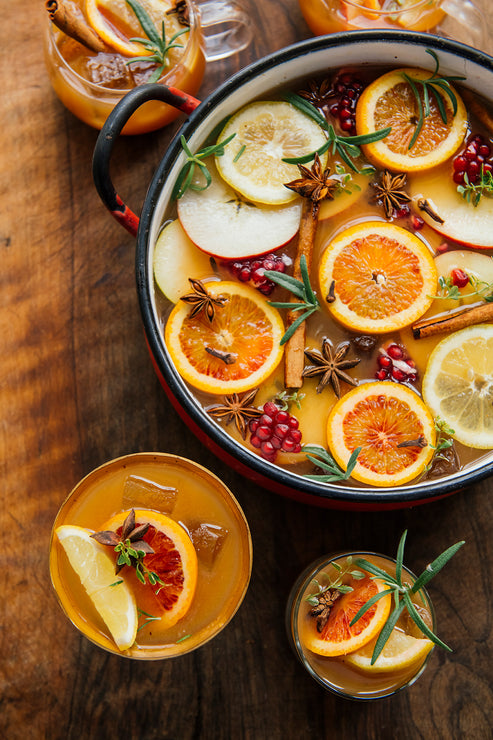 Load image into Gallery viewer, Punch bowl with Spiced Cider Punch, with 4 glasses of punch circling it. Punch bowl has apple and citrus slices, pomegranate, cinnamon sticks, star anise and snips of fresh thyme and rosemary in it.