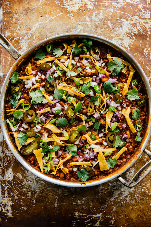 Load image into Gallery viewer, a pot of the People's Chili topped with tortilla chips, fresh cilantro, and pickled jalapeno slices