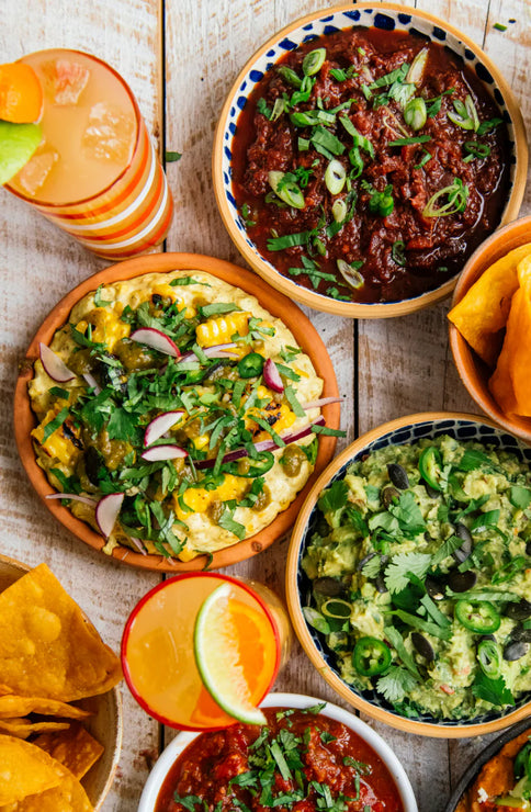 Load image into Gallery viewer, bowls of guacamole, chips, salsa, bean dip, street corn dip and glasses of margaritas
