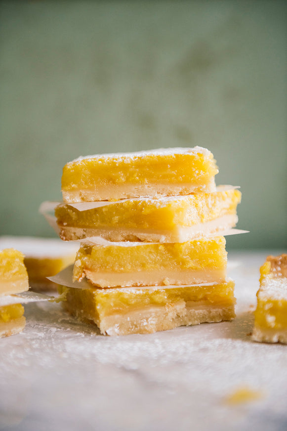 Stack of lemon bars on a marble surface with a blurred green background