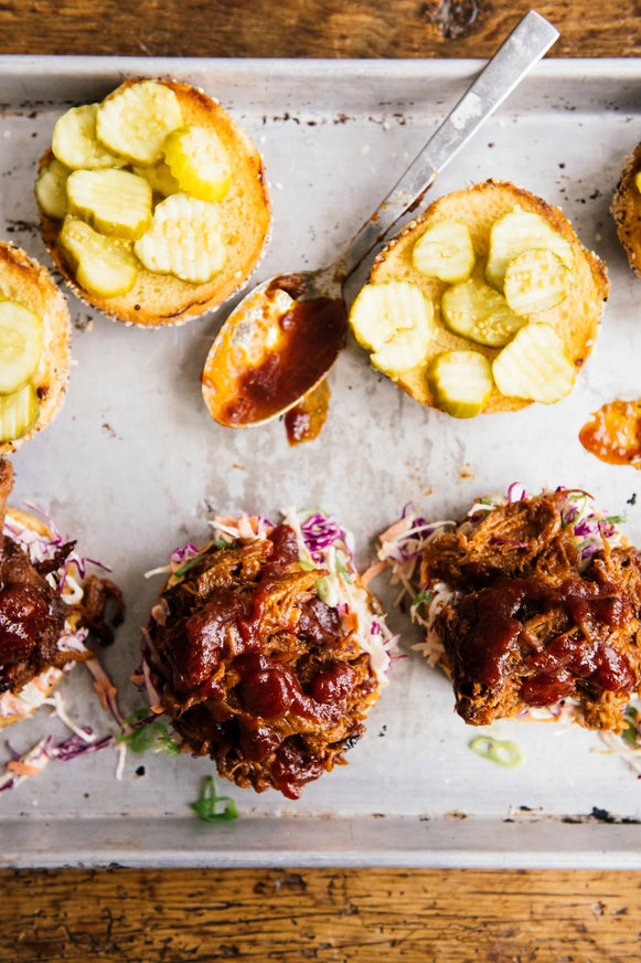 pulled pork sandwiches topped with slaw, pickles and bbq sauce