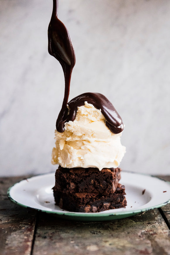 homemade brownies topped with vanilla ice cream and fudge sauce