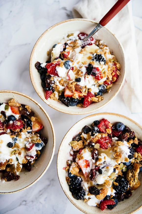 bowls of yogurt topped with maple granola and fresh berries