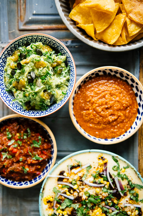 Load image into Gallery viewer, Chips, salsas, queso fundido and guacamole adorned with pepitas, slivered jalapeños and Tomatillo Salsa
