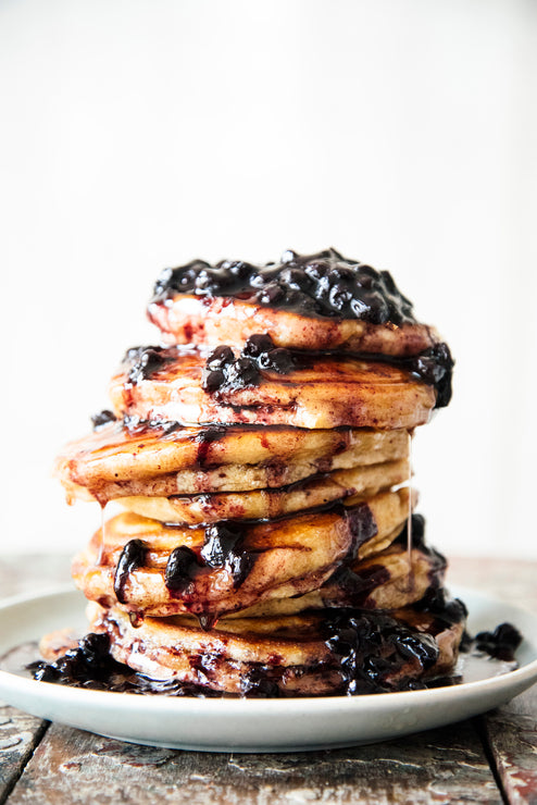 Load image into Gallery viewer, a stack of pancakes topped with blueberries and maple syrup
