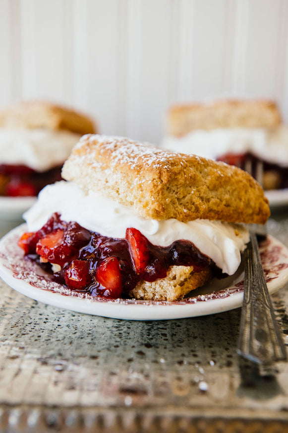 Single homemade biscuit with whipped cream and fresh strawberries in the middle