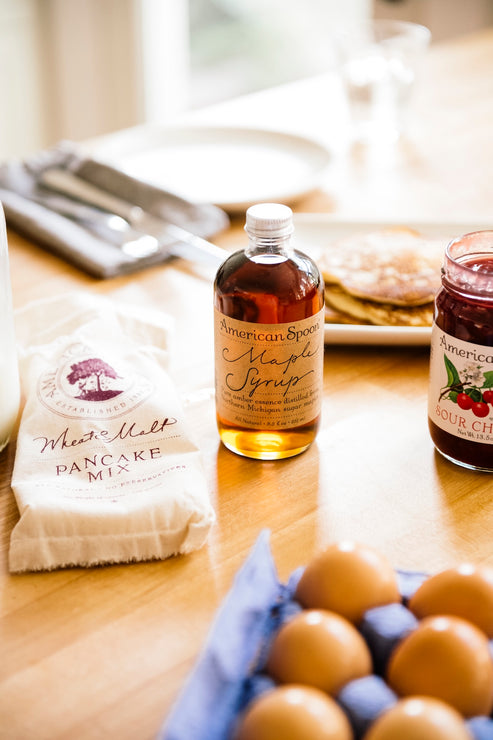 Load image into Gallery viewer, Bottle of maple syrup, pancake mix, Fruit Perfect Sour Cherries and eggs on a table  with blurred pancakes, a plate and silverware in the background
