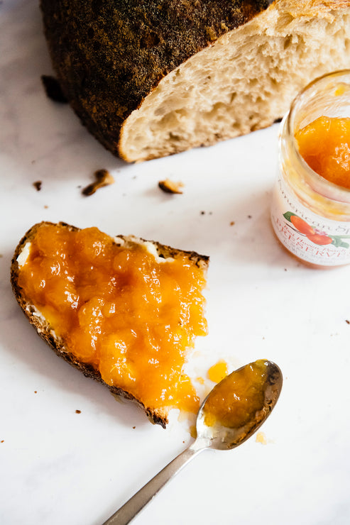 Load image into Gallery viewer, a slice of toast topped with red haven peach preserves next to a loaf of bread
