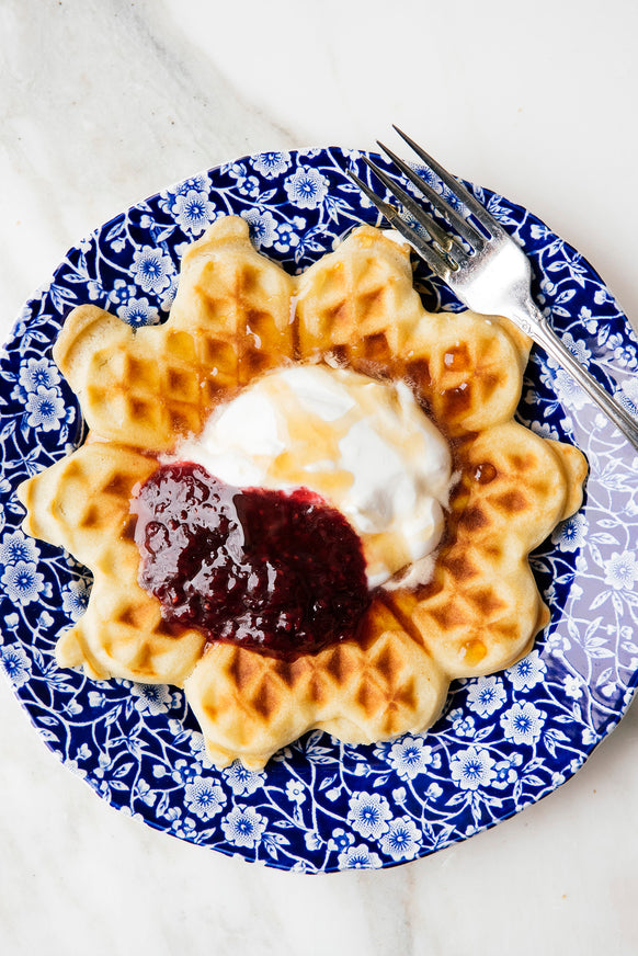 a waffle topped with fresh cream and preserves