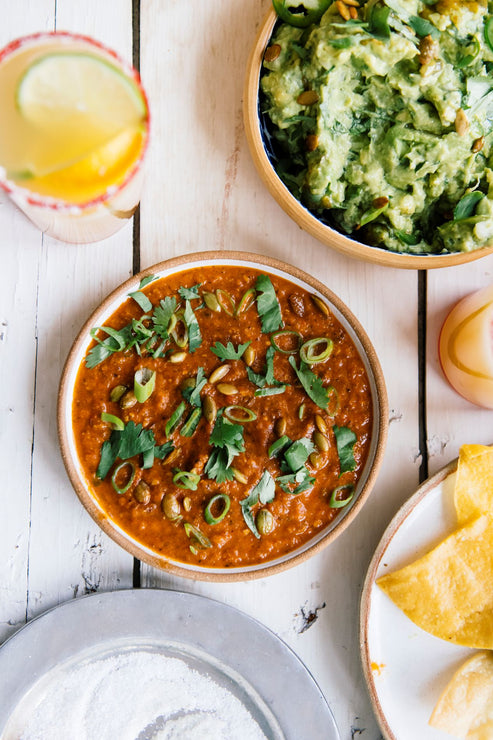 Load image into Gallery viewer, a bowl of pumpkin seed salsa next to a bowl of homemade guacamole and glasses of margaritas
