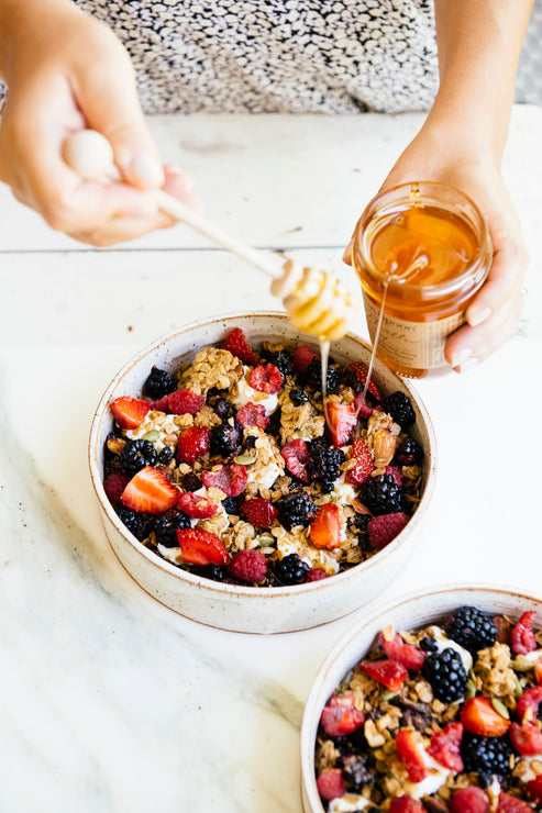 Load image into Gallery viewer, topping a bowl of granola and fresh berries with star thistle honey
