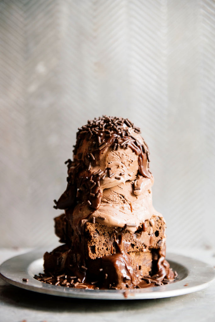 a brownie sundae topped with chocolate fudge sauce and chocolate sprinkles