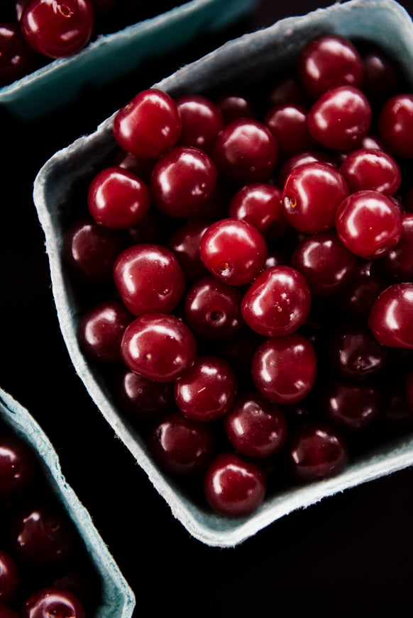 Close-up of red cherries in a blue fruit pint basket.