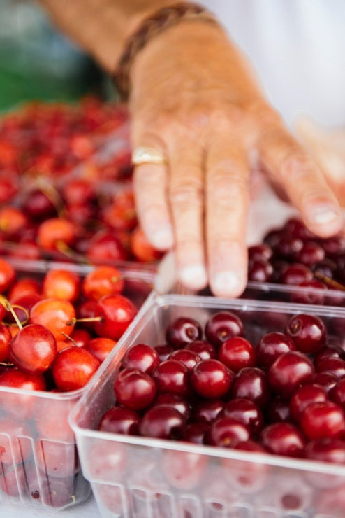 Load image into Gallery viewer, someone selecting baskets of farm market cherries
