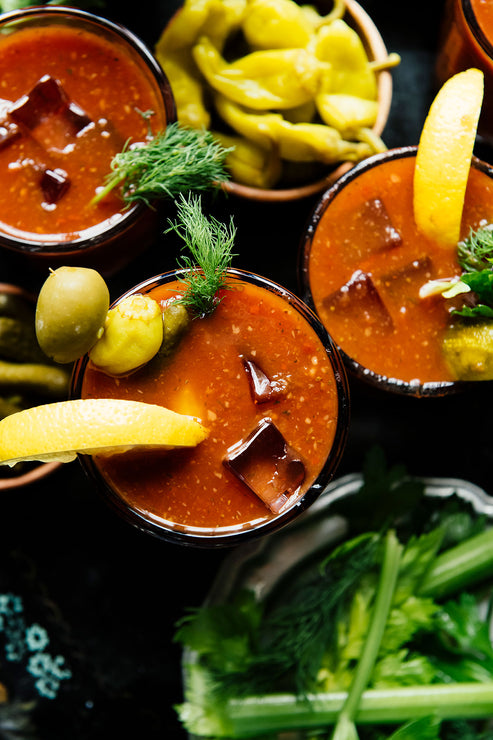 Load image into Gallery viewer, Three Bloody Mary cocktails with garnishes on a dark surface
