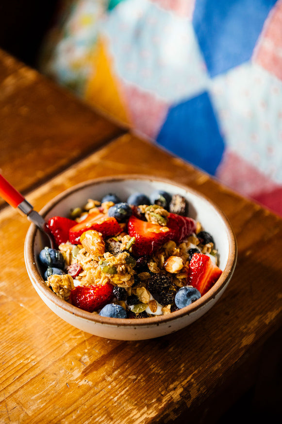 Bowl of Granola on a wooden table with fresh berries