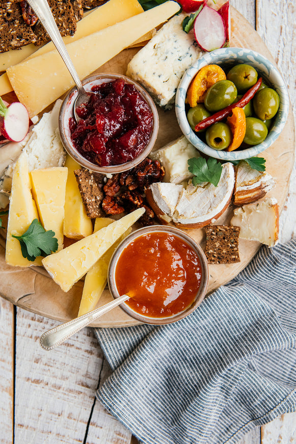 a charcuterie tray of cheeses, crackers, olives, candied pecans and various preserves and jams