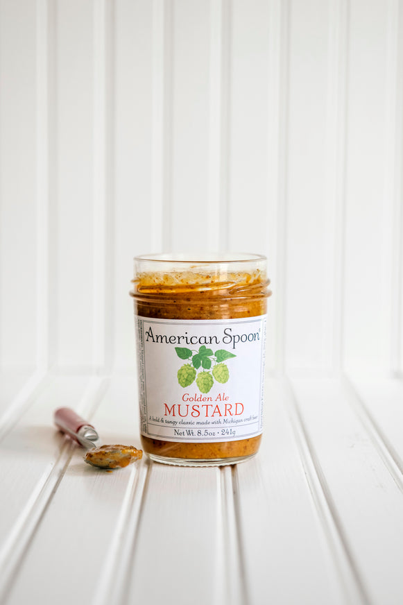 A jar of American Spoon Golden Ale Mustard set against a white beadboard background.