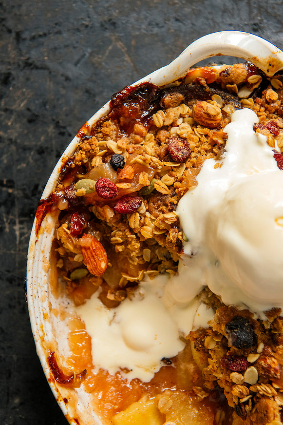 peach gobbler topped with maple granola and fresh vanilla ice cream