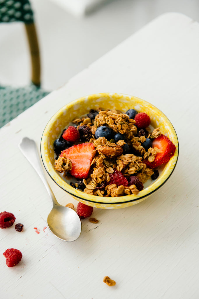 Bowl of granola with berries on a white surface