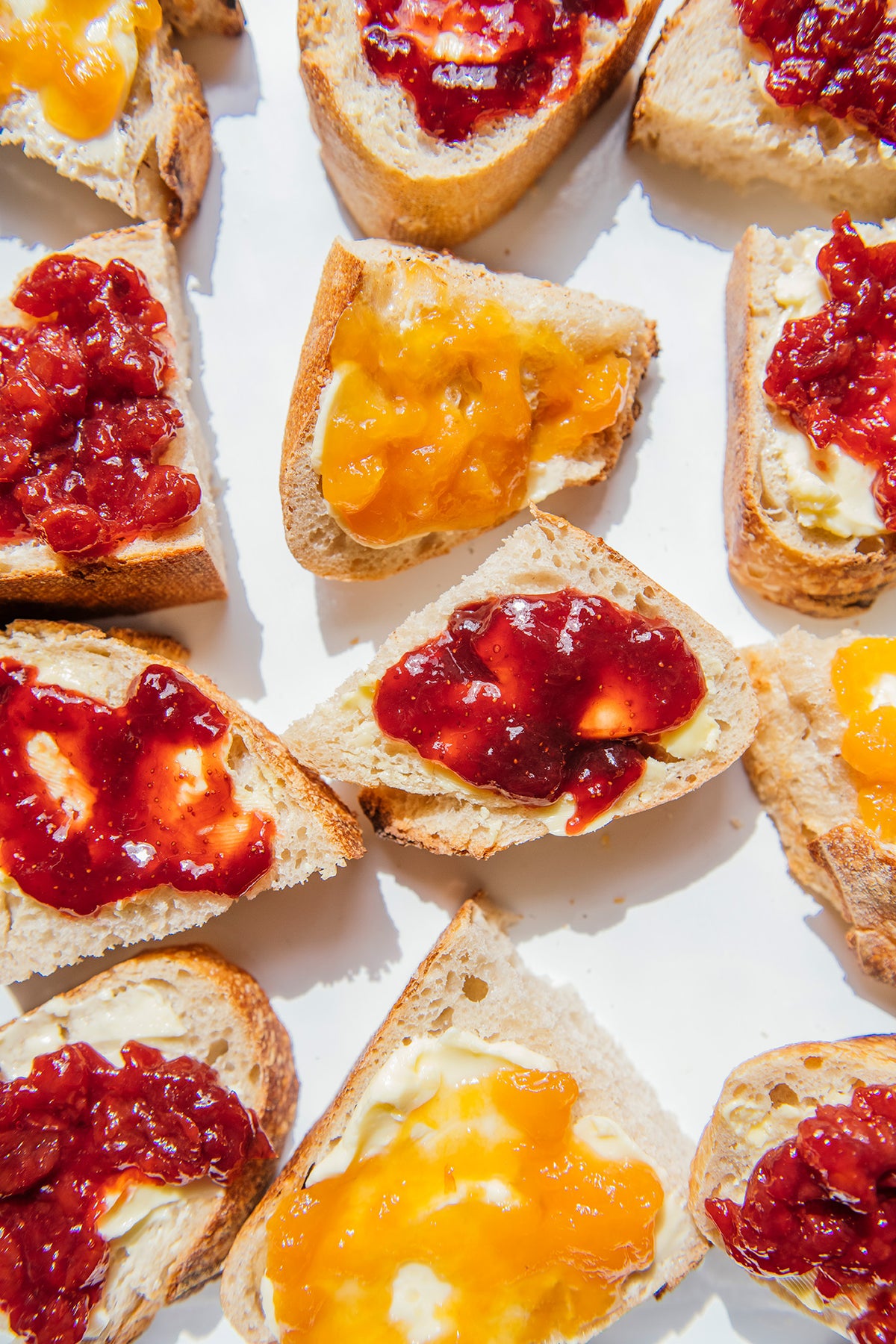 Toast slices with different types of jams on a white background