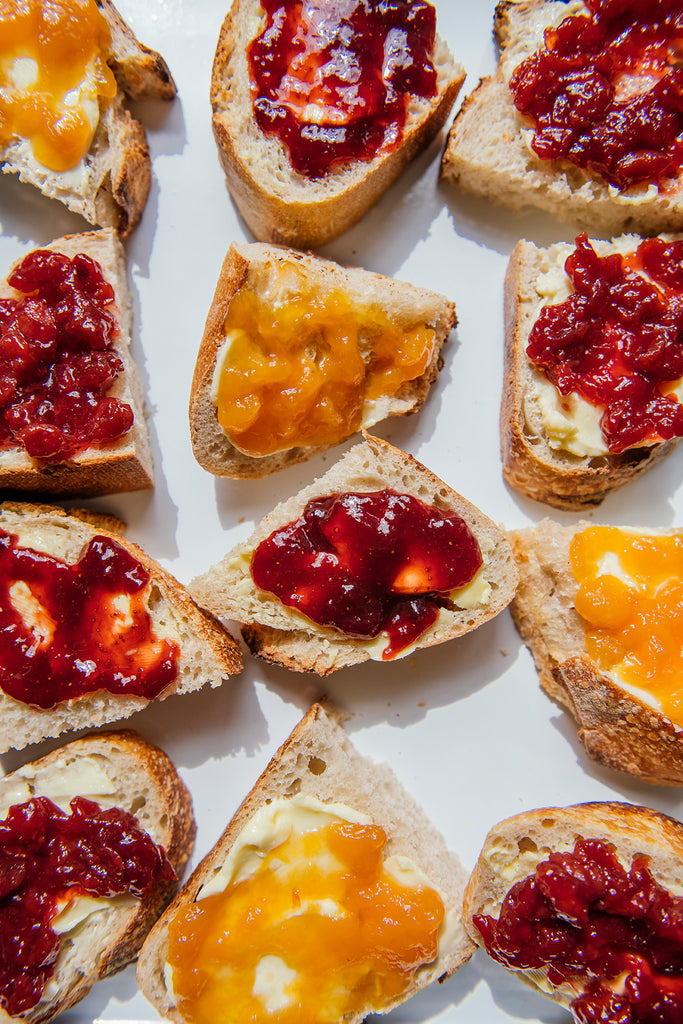 Toast slices with different types of jams on a white background