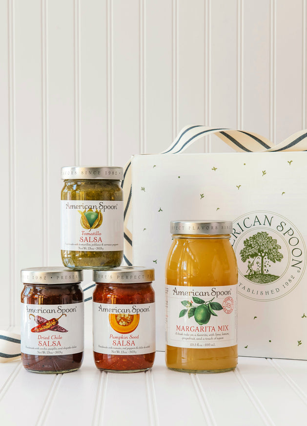 American Spoon Tomatillo, Dried Chili & Pumpkin Seed salsa and Margarita mix bottles with a branded box on a white surface.
