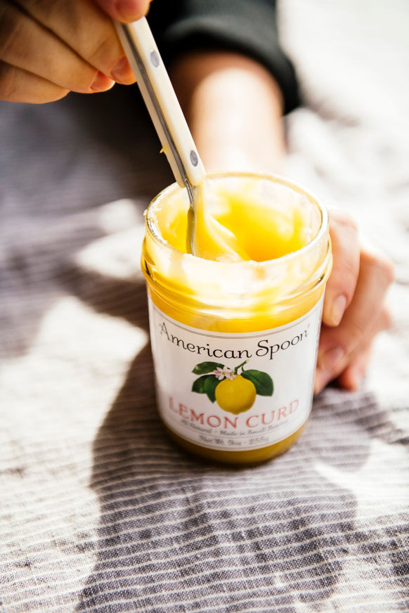 dipping into a jar of lemon curd with a spoon