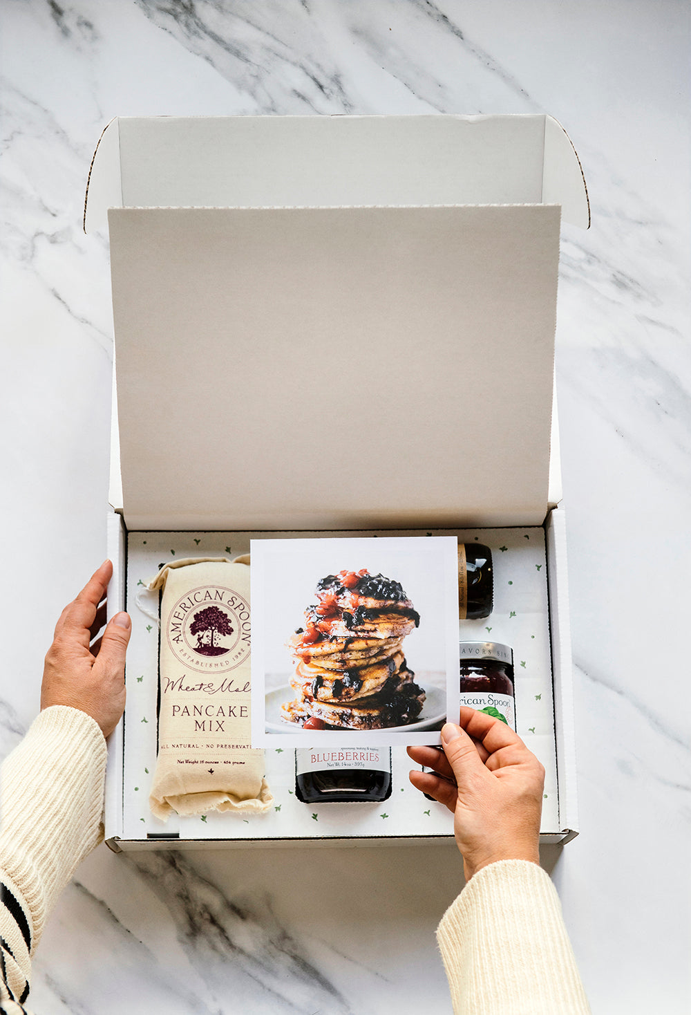 someone opening a classic pancake breakfast box with Wheat & Malt Pancake Mix, Maple Syrup, Fruit Perfect Blueberries and Fruit Perfect Sour Cherries