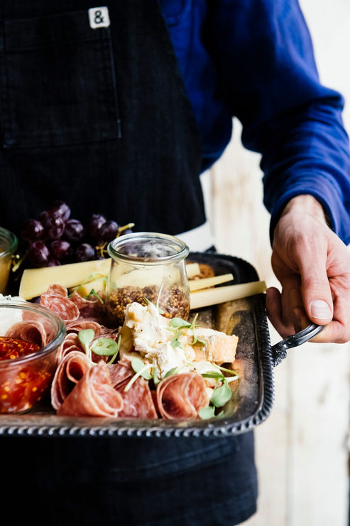 Load image into Gallery viewer, someone holding a charcuterie tray of meats, cheese and spread
