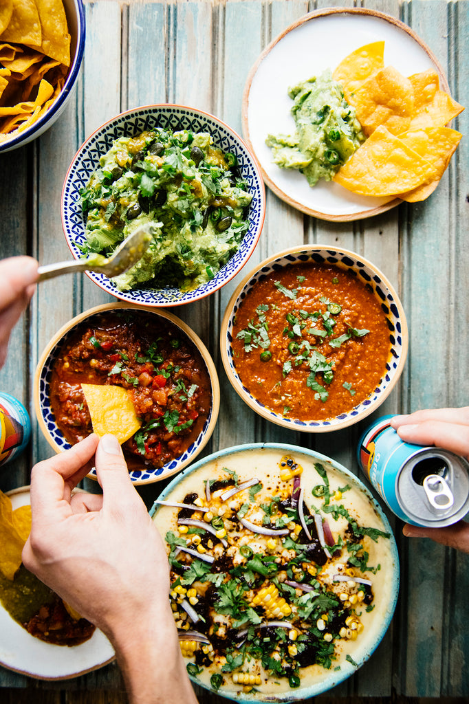 Dipping chips into of American Spoon Salsa, Queso with Dried Chili Salsa and fresh guacamole