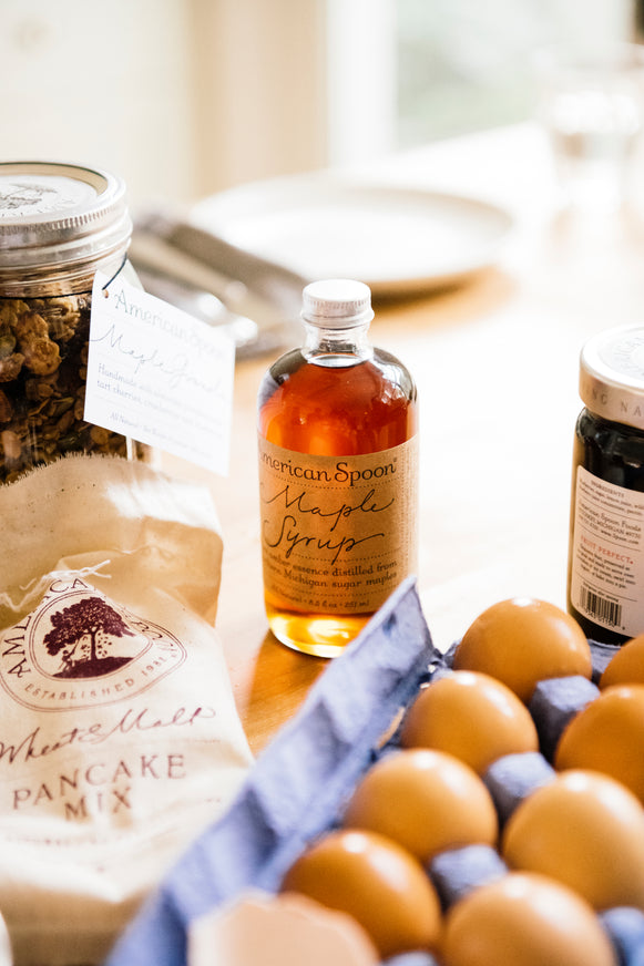 A kitchen counter full of Wheat & Malt pancake Mix, Maple Syrup, Maple Granola and a carton of eggs