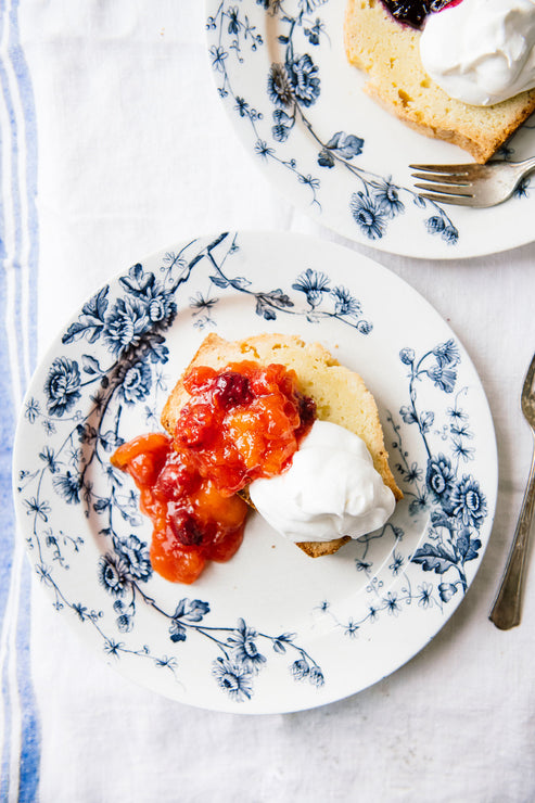 Load image into Gallery viewer, Slices of pound cake topped with Stone Fruit Compote and whipped cream on blue and white floral plates with forks.
