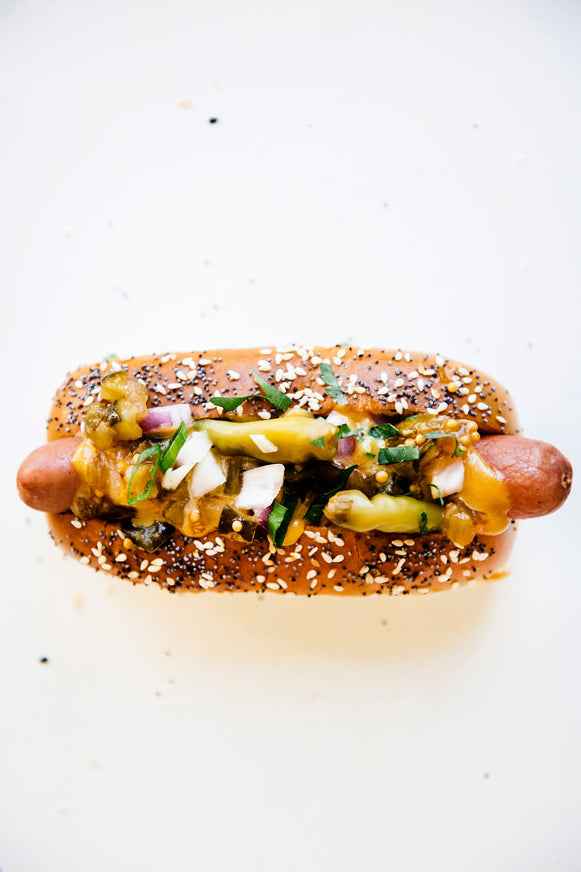 A hot dog topped with peppers, onion, and American Spoon mustard