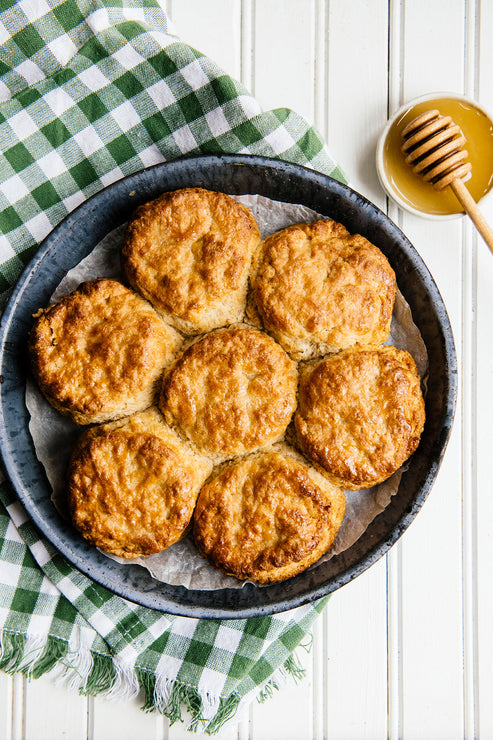 Load image into Gallery viewer, Skillet of homemade biscuits with honey dipper and honey set to the side.
