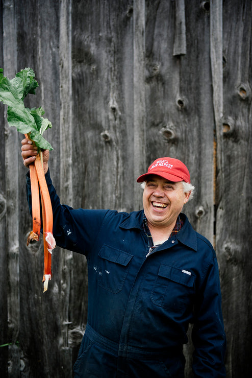 Load image into Gallery viewer, Bill McMaster of Bill's Farm Market holding stalks of rhubarb
